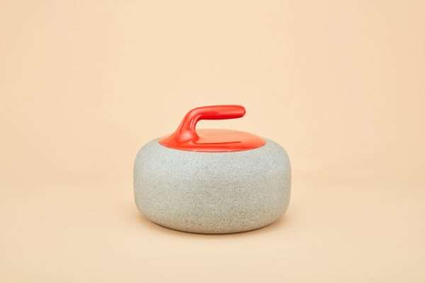 An urn that looks like a curling stone. A red handle and stone base