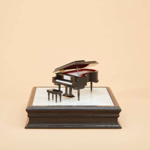An urn that looks like a piano atop a pedestal