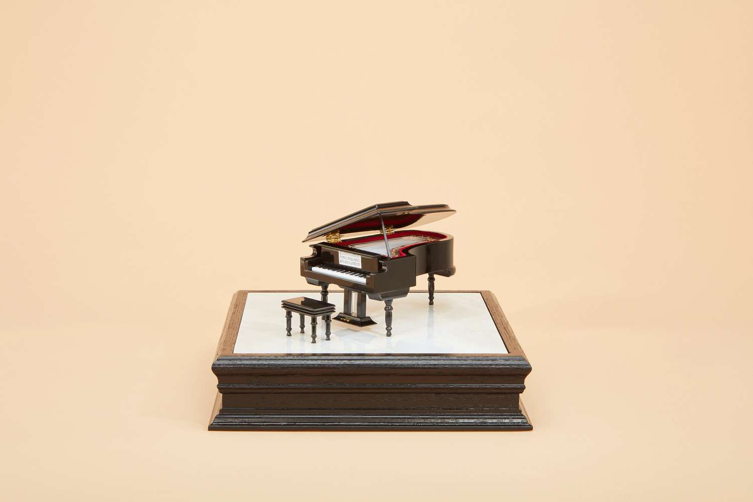 An urn that looks like a piano atop a pedestal