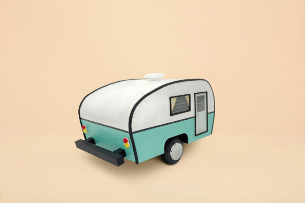 An urn that looks like a white and mint blue trailer camper. It has wheels and a propane tank, door and windows with curtains