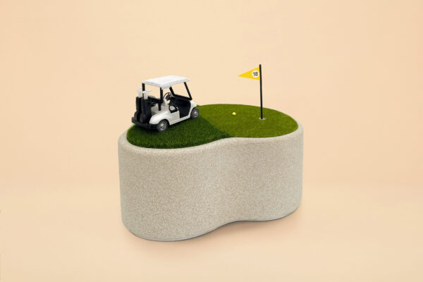 An urn that looks like a golf cart on the putting green. There is a yellow flag and golf hole