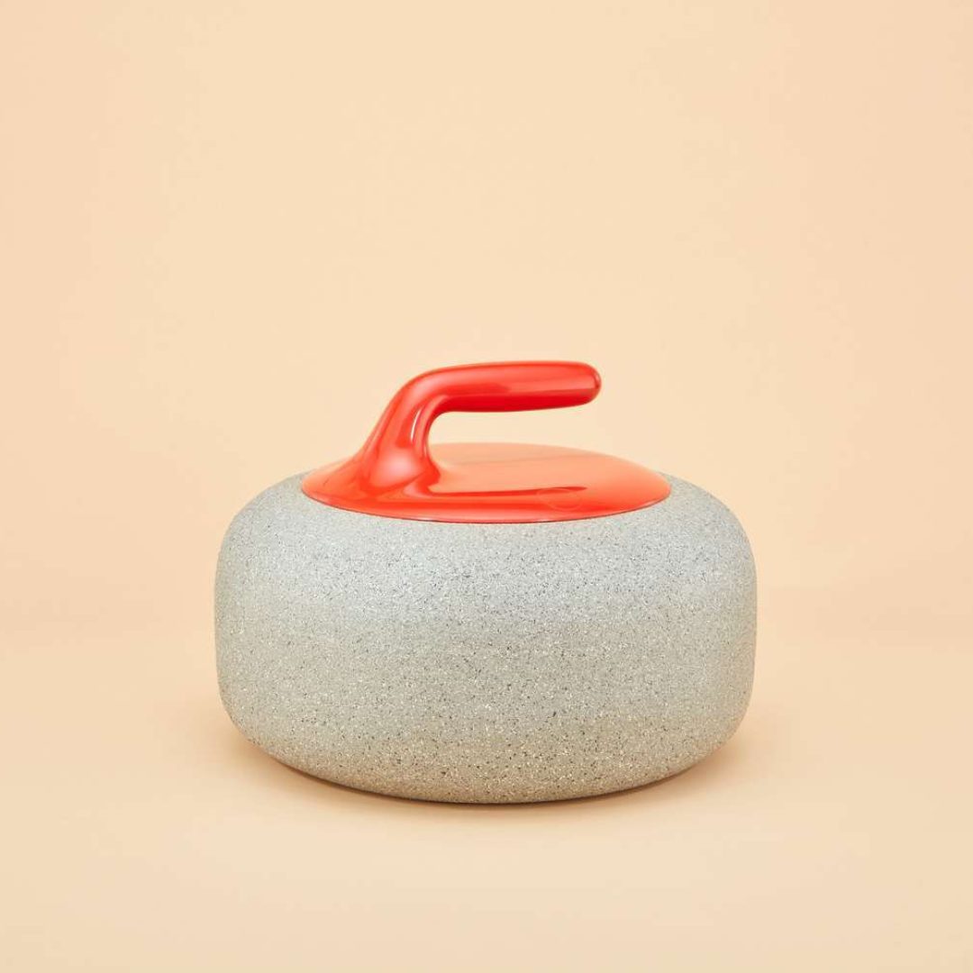 An urn that looks like a curling stone. A red handle and stone base